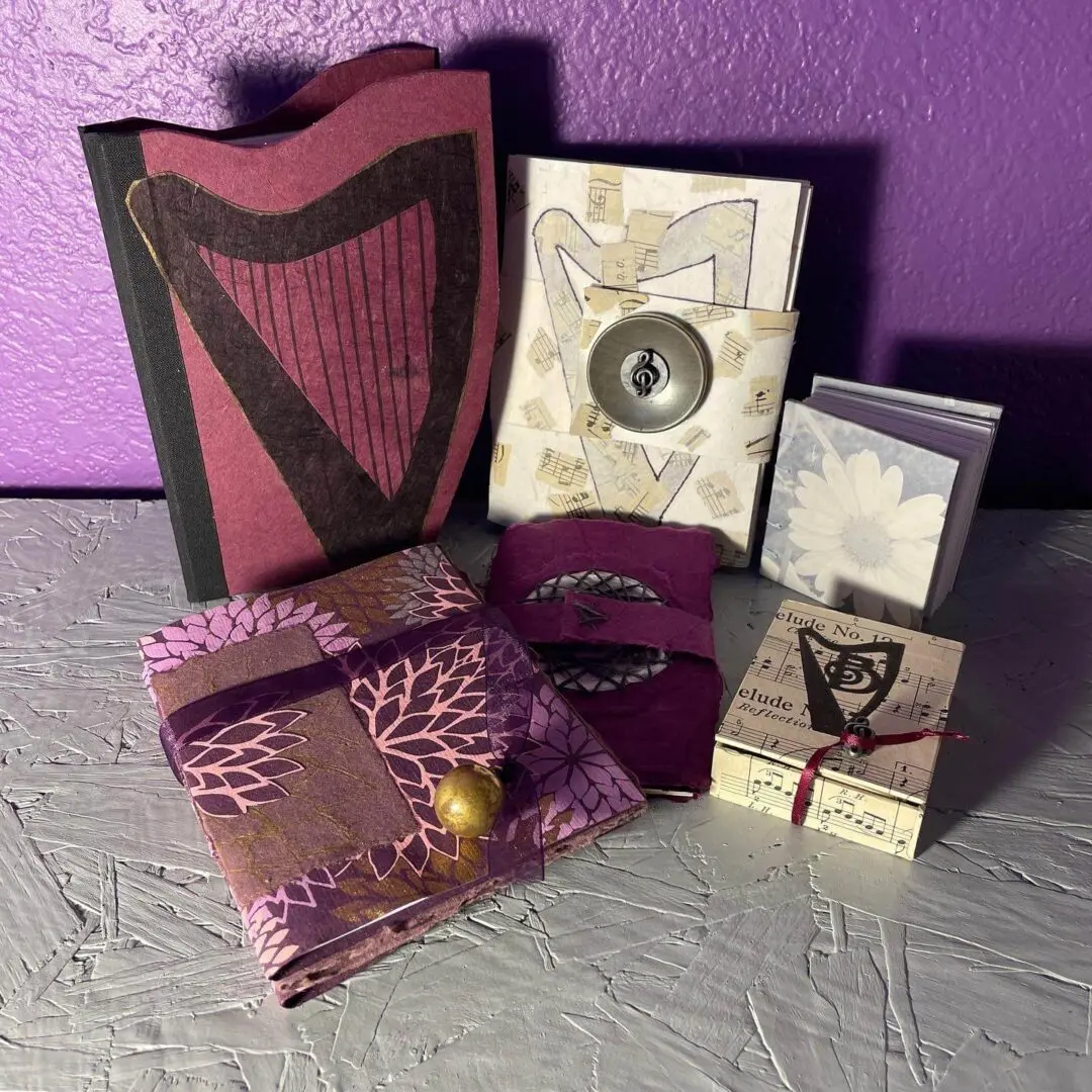 Purple and gold handmade journals with harp design.