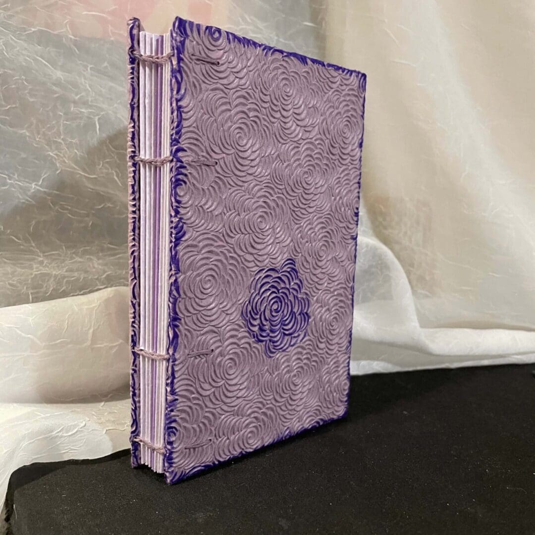 Purple leather bound book with rose design.