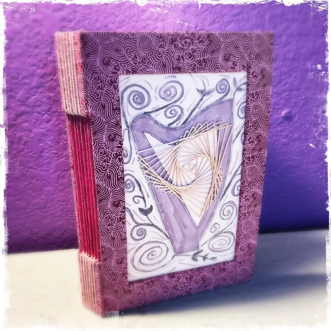 Purple book with a harp design.