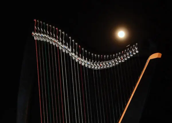 A harp is shown in front of the moon.