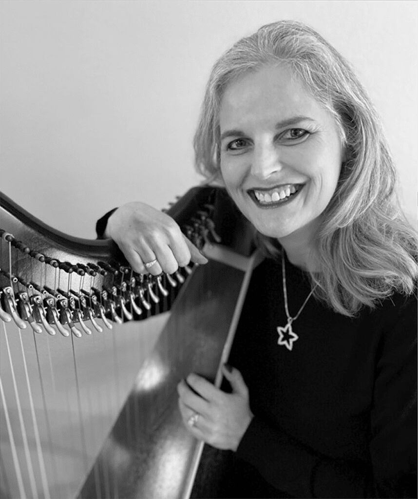 A woman holding a harp and smiling.